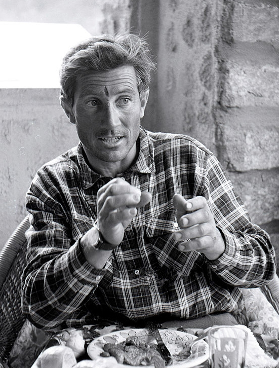 Walter Bonatti sits with a lunch tray on his knees, while talking and gesticulating; he is back from climbing Pointe Whymper in Grandes Jorasses, with the Swiss mountain climber Michel Vaucher. Grandes Jorasses, Mont Blanc (France), 1964.